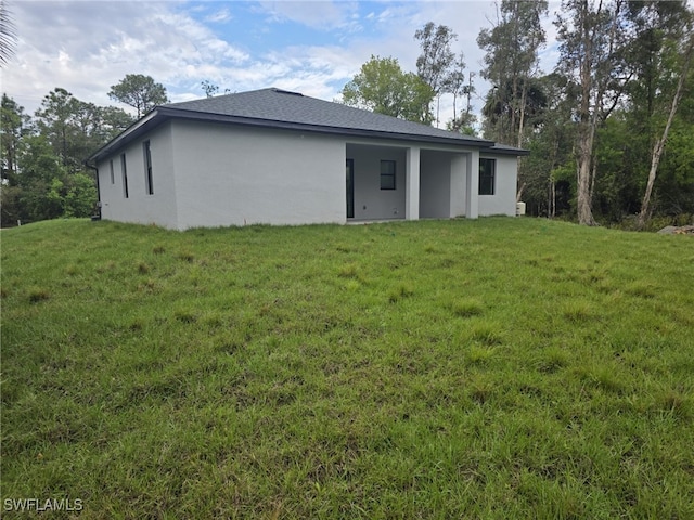 back of property with a lawn and stucco siding