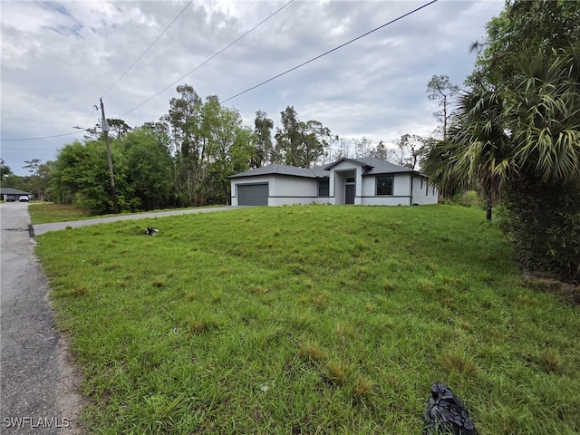 view of front of home featuring a garage, driveway, a front lawn, and stucco siding