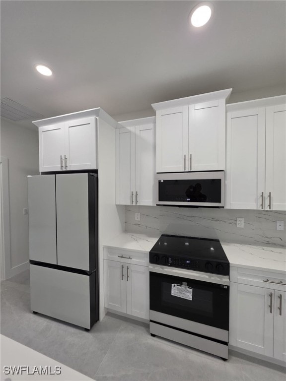 kitchen with range with electric cooktop, freestanding refrigerator, and white cabinetry