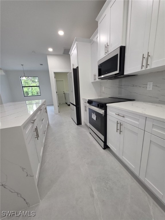 kitchen featuring freestanding refrigerator, stainless steel microwave, white cabinets, and range with electric stovetop