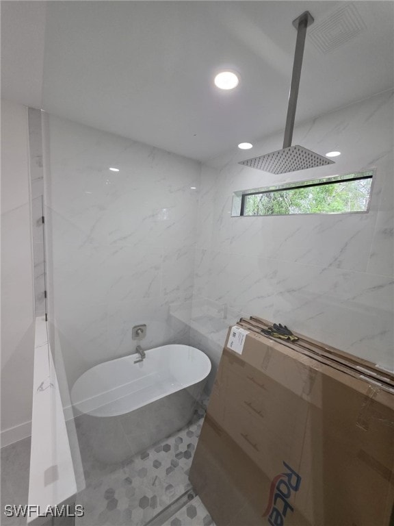 full bath with tile walls, walk in shower, a freestanding bath, and recessed lighting