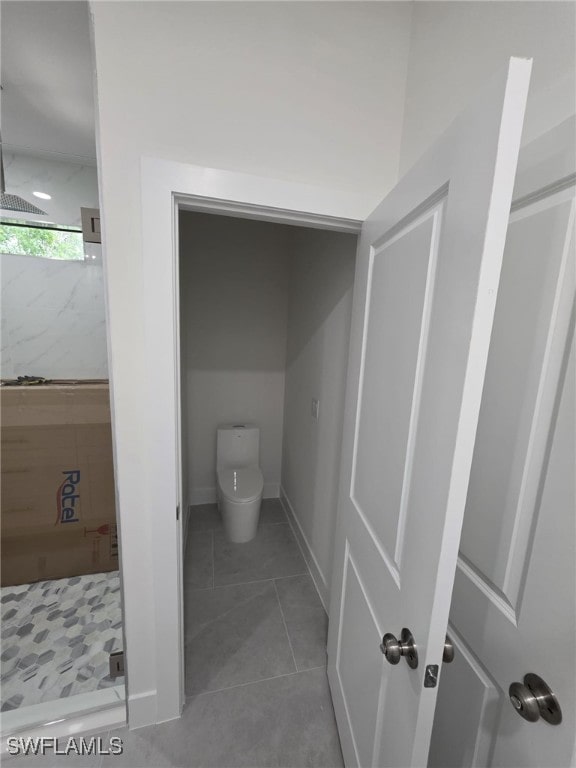 full bath with baseboards, a stall shower, toilet, and tile patterned floors