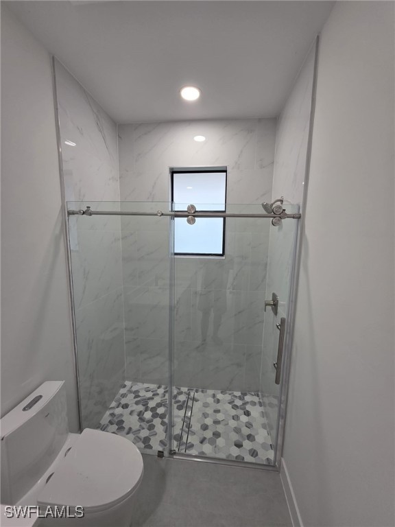 bathroom featuring recessed lighting, baseboards, a shower stall, and toilet