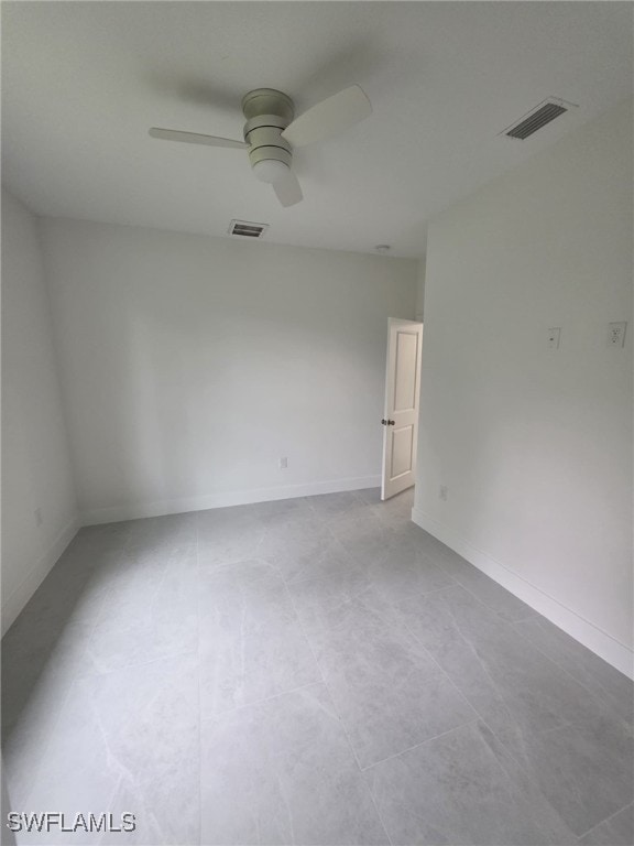 empty room featuring a ceiling fan, visible vents, and baseboards