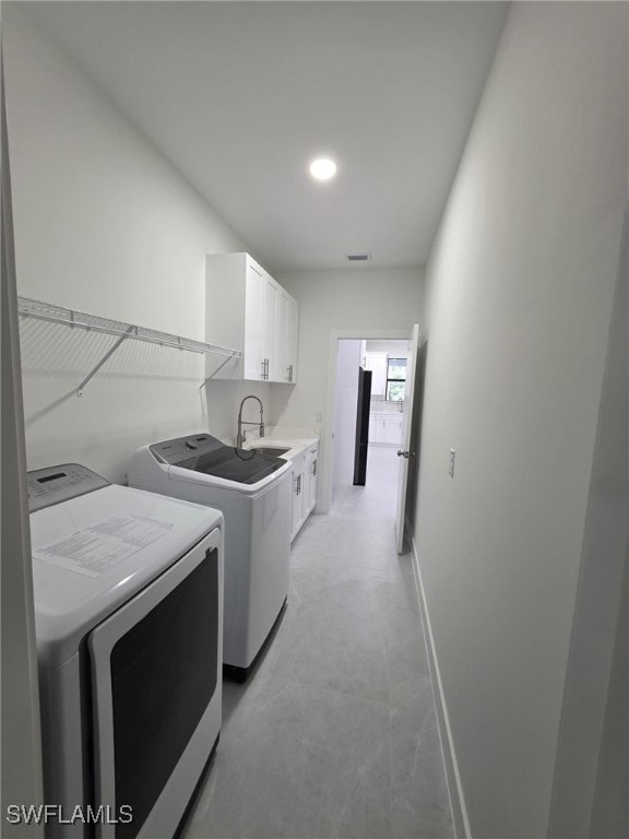 washroom with cabinet space, visible vents, baseboards, independent washer and dryer, and a sink