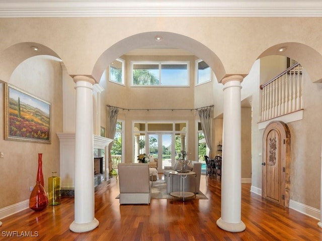 entryway featuring decorative columns, baseboards, dark wood-style flooring, and a high end fireplace