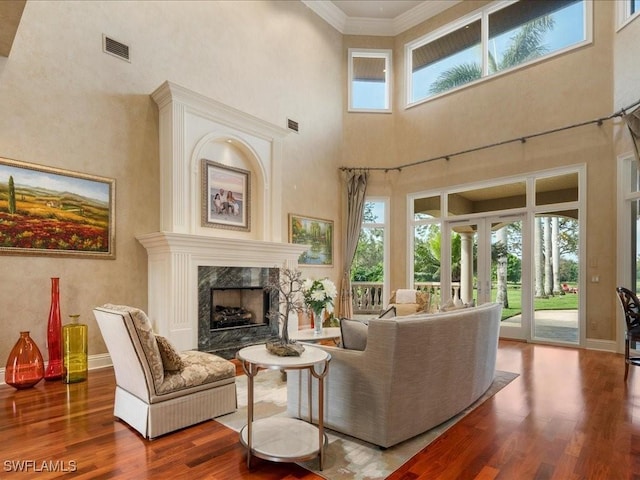 living area with baseboards, visible vents, ornamental molding, wood finished floors, and a fireplace