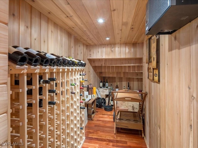 wine area with wooden ceiling, recessed lighting, wood finished floors, and wood walls