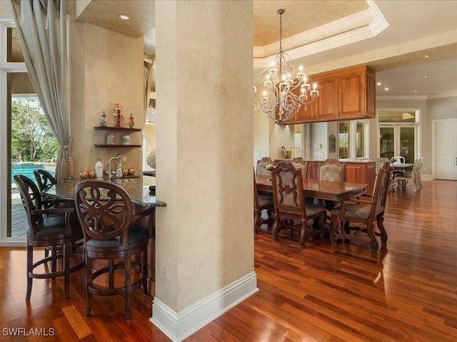 dining area featuring dark wood-type flooring, a notable chandelier, crown molding, and baseboards