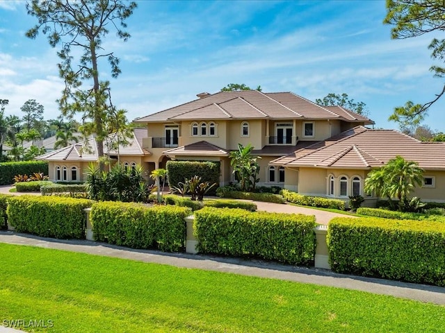 view of front facade featuring a tiled roof, a front yard, and stucco siding