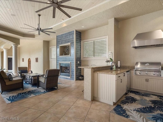 kitchen featuring a peninsula, wall chimney exhaust hood, open floor plan, and light countertops