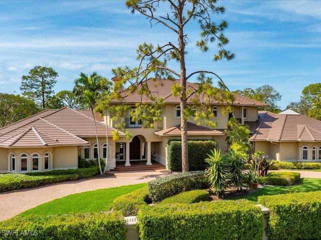 mediterranean / spanish home with decorative driveway, a tile roof, and stucco siding