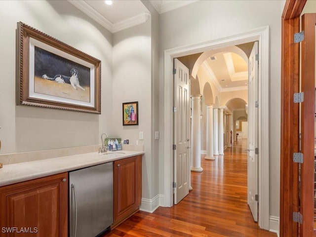 interior space with a sink, ornamental molding, arched walkways, and stainless steel fridge