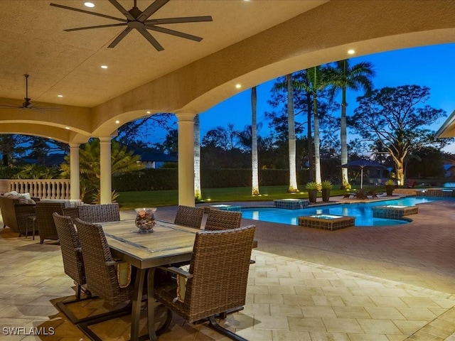 patio terrace at dusk featuring a ceiling fan, outdoor dining area, a fenced backyard, and a pool with connected hot tub