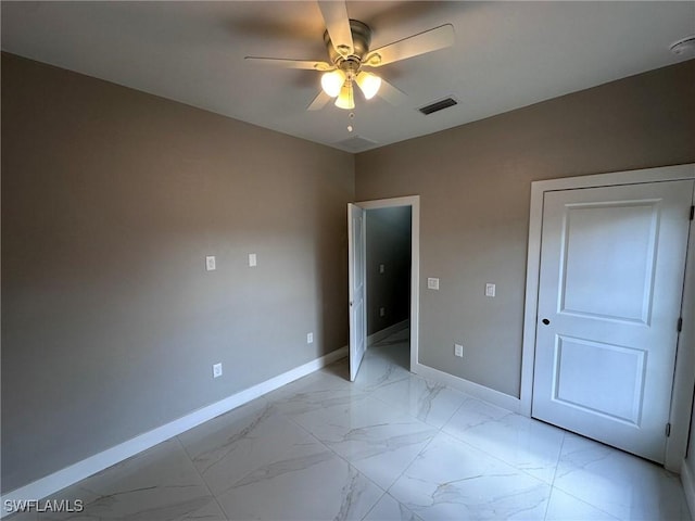 unfurnished bedroom featuring marble finish floor, visible vents, baseboards, and ceiling fan