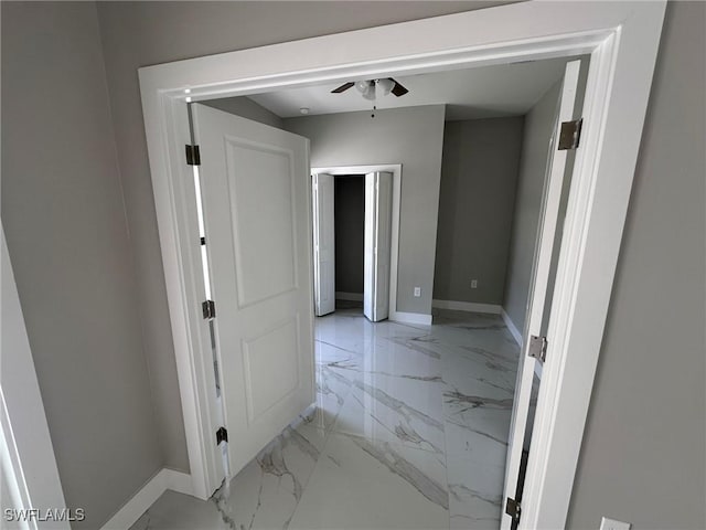 corridor featuring marble finish floor and baseboards