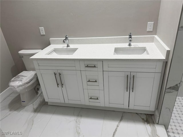 bathroom with marble finish floor, a sink, toilet, and double vanity