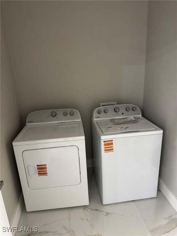 clothes washing area with washer and dryer, marble finish floor, baseboards, and laundry area