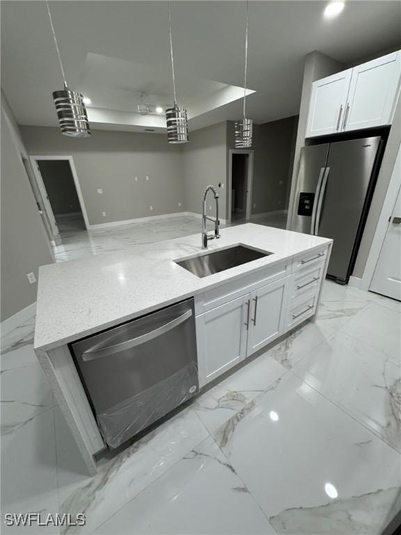 kitchen featuring appliances with stainless steel finishes, pendant lighting, white cabinetry, and a sink