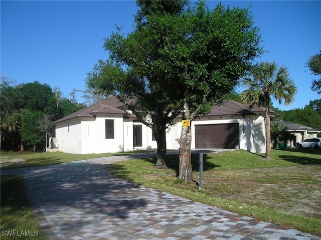 view of front of property with a front lawn, driveway, an attached garage, and stucco siding