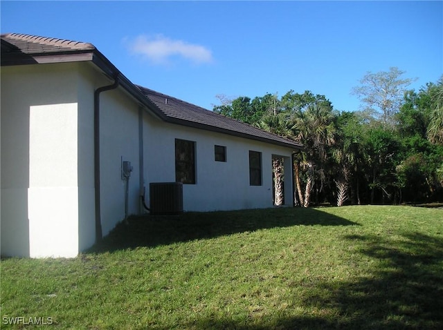 view of property exterior with central AC unit, a lawn, and stucco siding