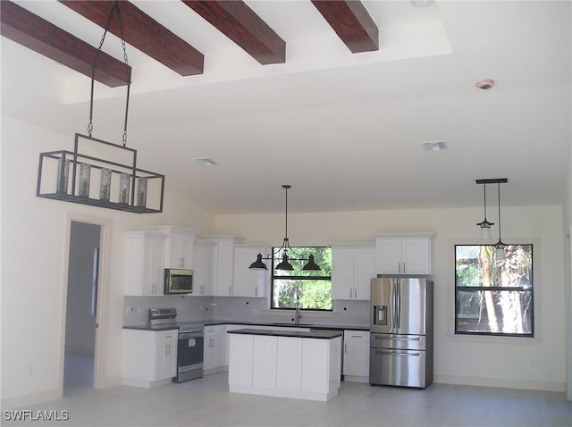 kitchen featuring appliances with stainless steel finishes, dark countertops, a sink, and backsplash