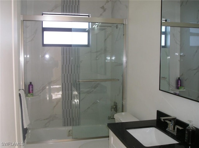 full bath with combined bath / shower with glass door, vanity, and toilet