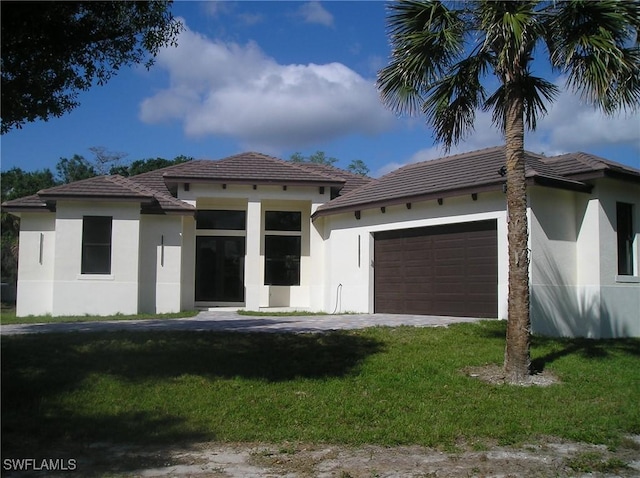 prairie-style house with a garage, a front lawn, and stucco siding