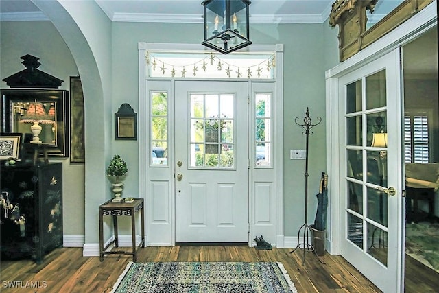 entryway featuring arched walkways, dark wood-style flooring, and crown molding