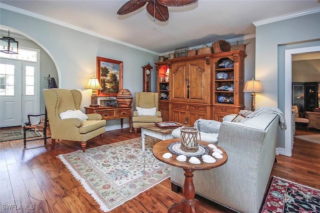 living area featuring arched walkways, dark wood-type flooring, and ornamental molding