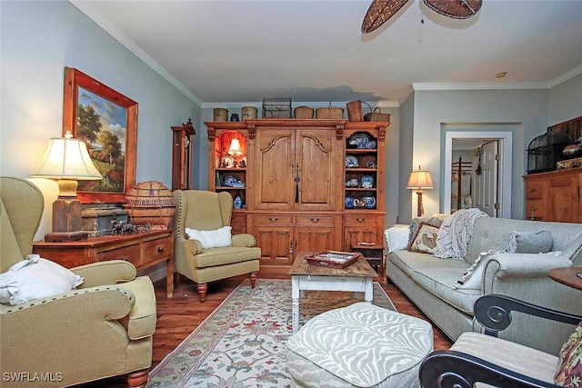 living area with ornamental molding, dark wood-style flooring, and a ceiling fan