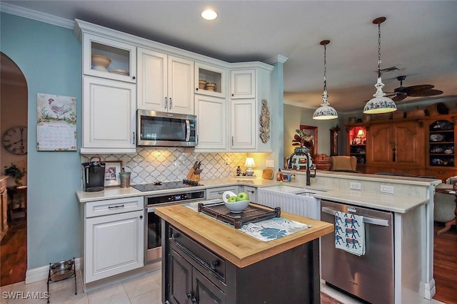 kitchen with stainless steel appliances, white cabinets, glass insert cabinets, and a peninsula