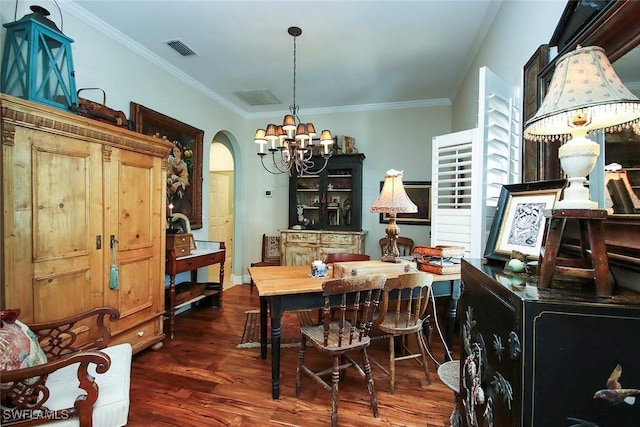 dining room featuring dark wood-type flooring, a chandelier, visible vents, and ornamental molding