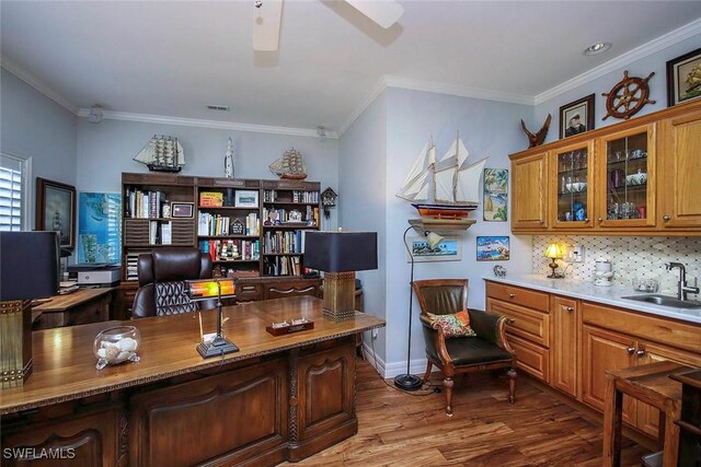 office space with a ceiling fan, a sink, crown molding, and wood finished floors