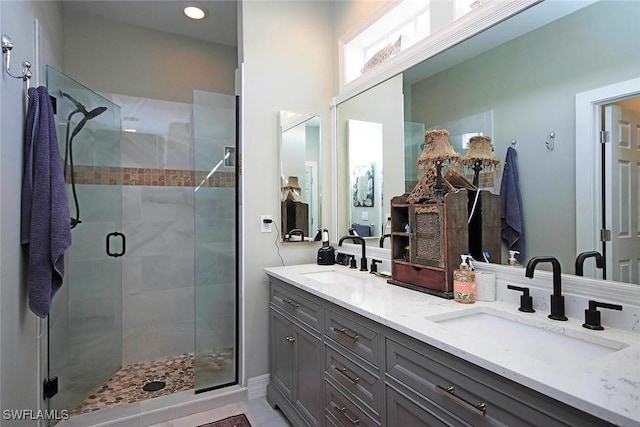 full bath featuring double vanity, a stall shower, a sink, and recessed lighting