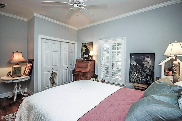 bedroom featuring wood finished floors, visible vents, baseboards, a closet, and crown molding