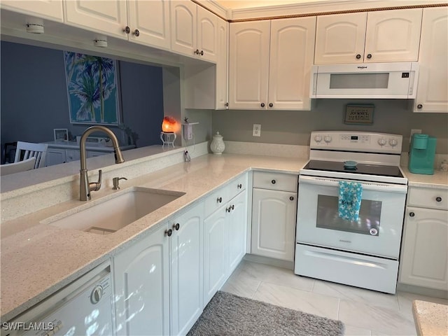 kitchen featuring white appliances, a sink, white cabinets, marble finish floor, and light stone countertops