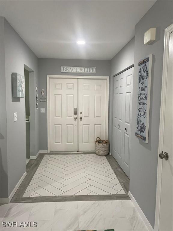 foyer entrance with marble finish floor and baseboards