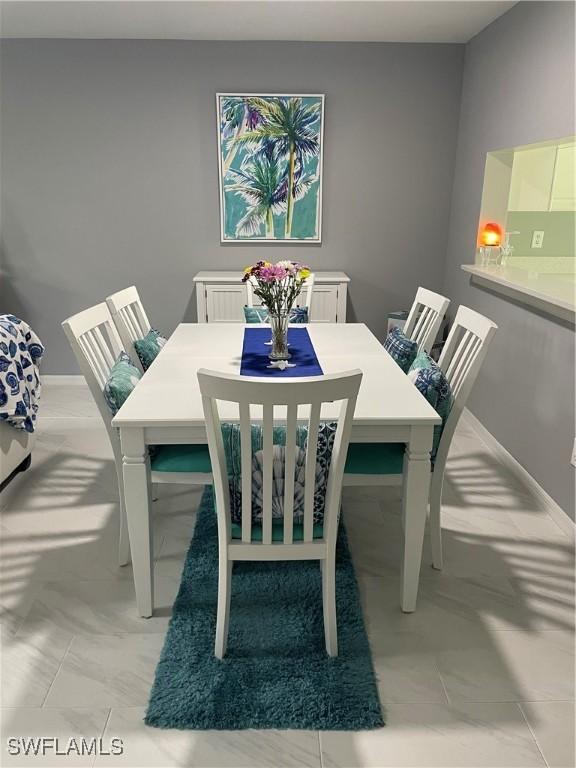 dining area featuring marble finish floor and baseboards