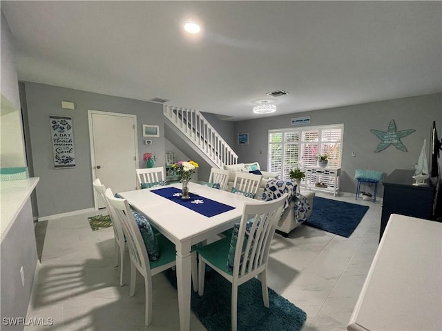 dining room featuring marble finish floor, stairway, visible vents, and baseboards