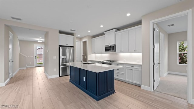 4568 Centaurus Cir, Naples, FL 34120 - kitchen featuring stainless steel appliances, a sink, light wood-style flooring, white cabinetry, and healthy amount of natural light
