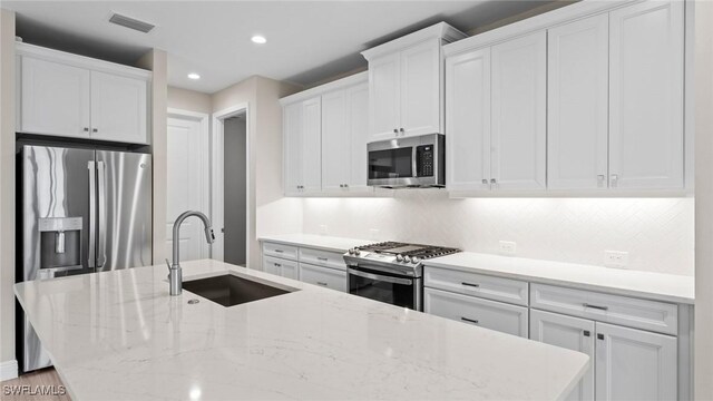 4568 Centaurus Cir, Naples, FL 34120 - kitchen featuring stainless steel appliances, a sink, white cabinets, a center island with sink, and recessed lighting
