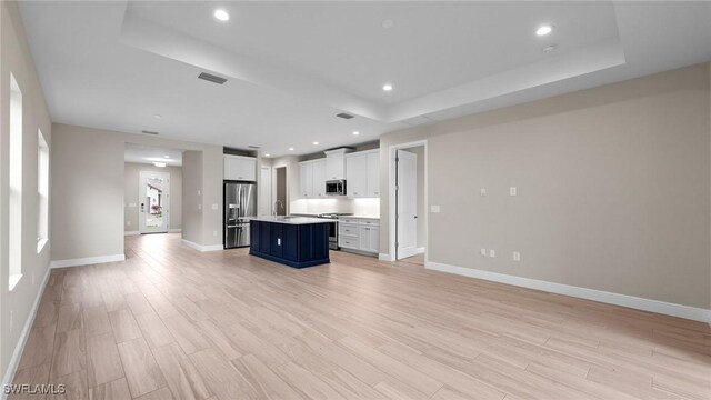 4568 Centaurus Cir, Naples, FL 34120 - kitchen with stainless steel appliances, a raised ceiling, open floor plan, an island with sink, and white cabinetry