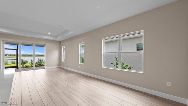 4568 Centaurus Cir, Naples, FL 34120 - empty room with baseboards, light wood-style flooring, a water view, a tray ceiling, and recessed lighting