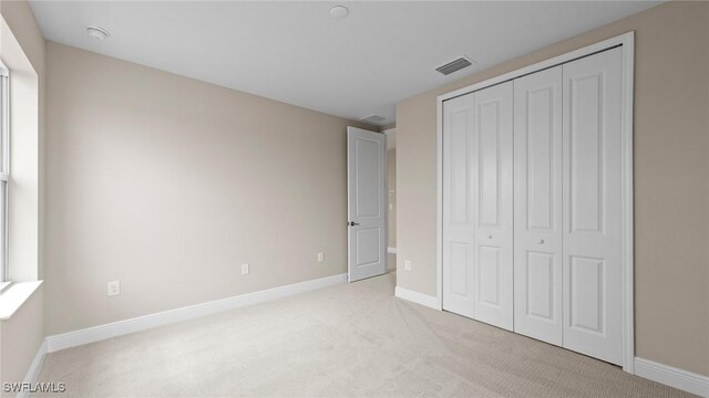4568 Centaurus Cir, Naples, FL 34120 - unfurnished bedroom featuring light carpet, baseboards, and a closet