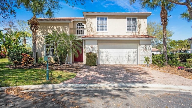 mediterranean / spanish-style house with decorative driveway, an attached garage, a tile roof, and stucco siding