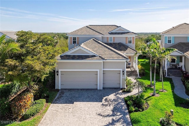 view of front of property featuring a garage, a tile roof, and decorative driveway