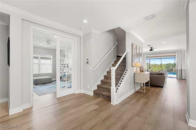 entryway featuring light wood-style flooring, ceiling fan, and crown molding