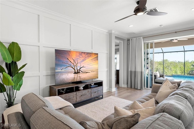 living room featuring a sunroom, ceiling fan, a decorative wall, and crown molding