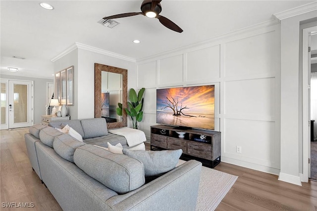 living area featuring a decorative wall, wood finished floors, a ceiling fan, french doors, and ornamental molding